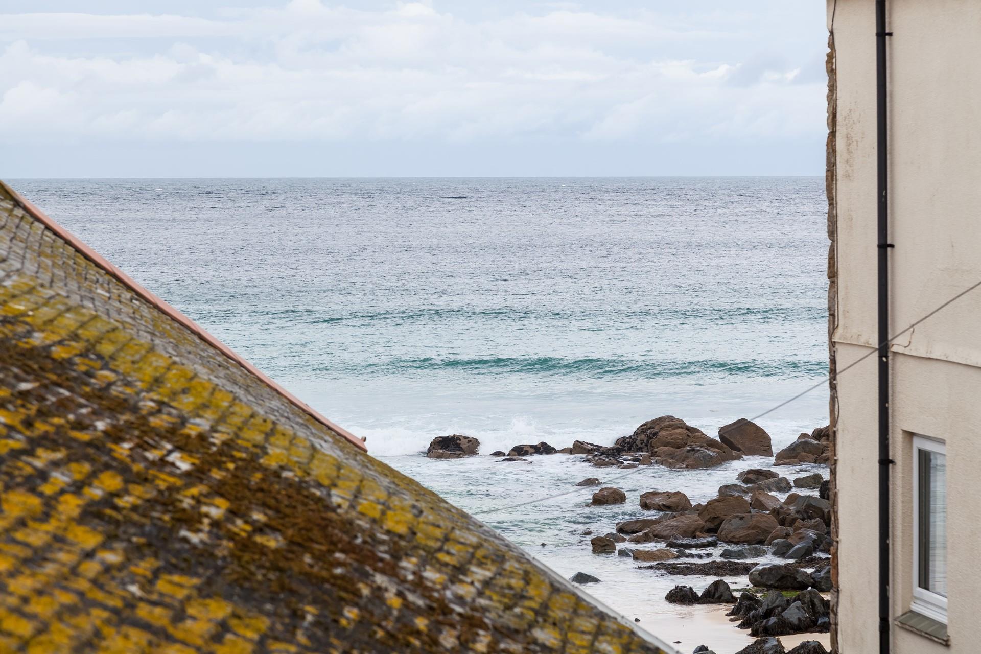 The sea view across the St Ives sea and the beach can be seen over the rooftops. 