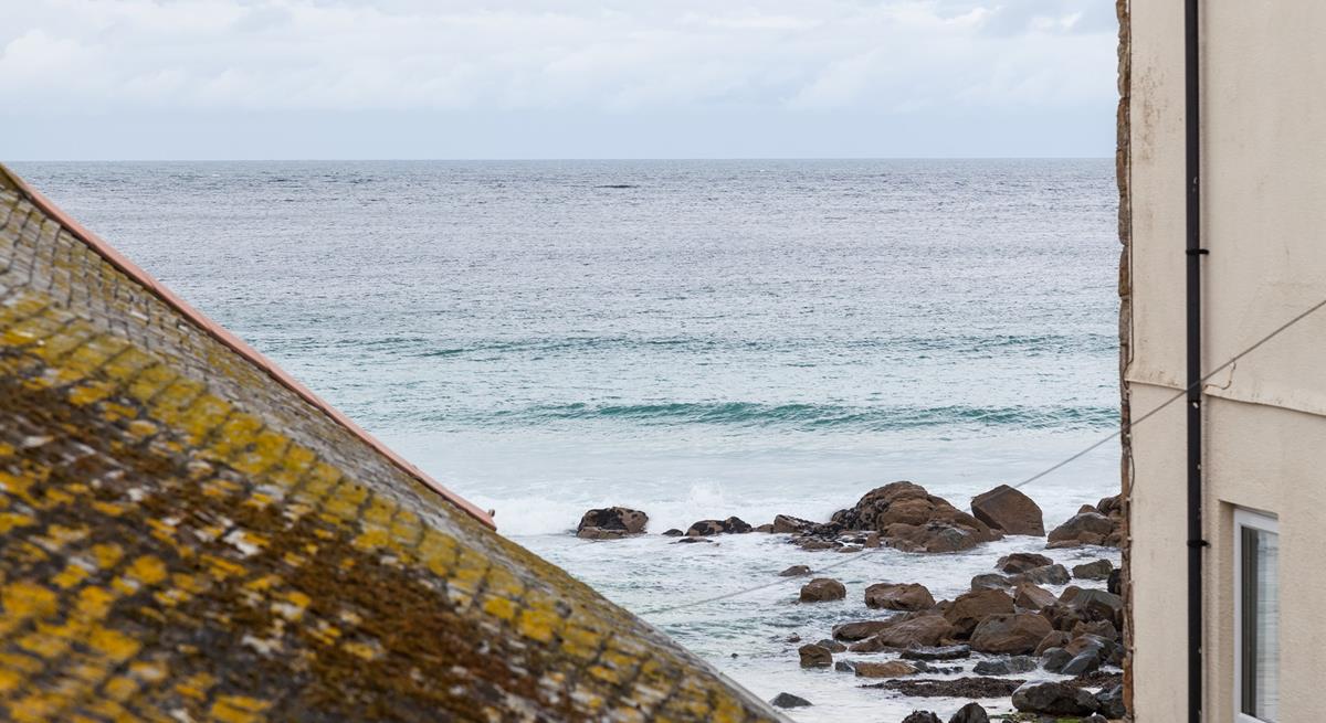 The sea view across the St Ives sea and the beach can be seen over the rooftops. 