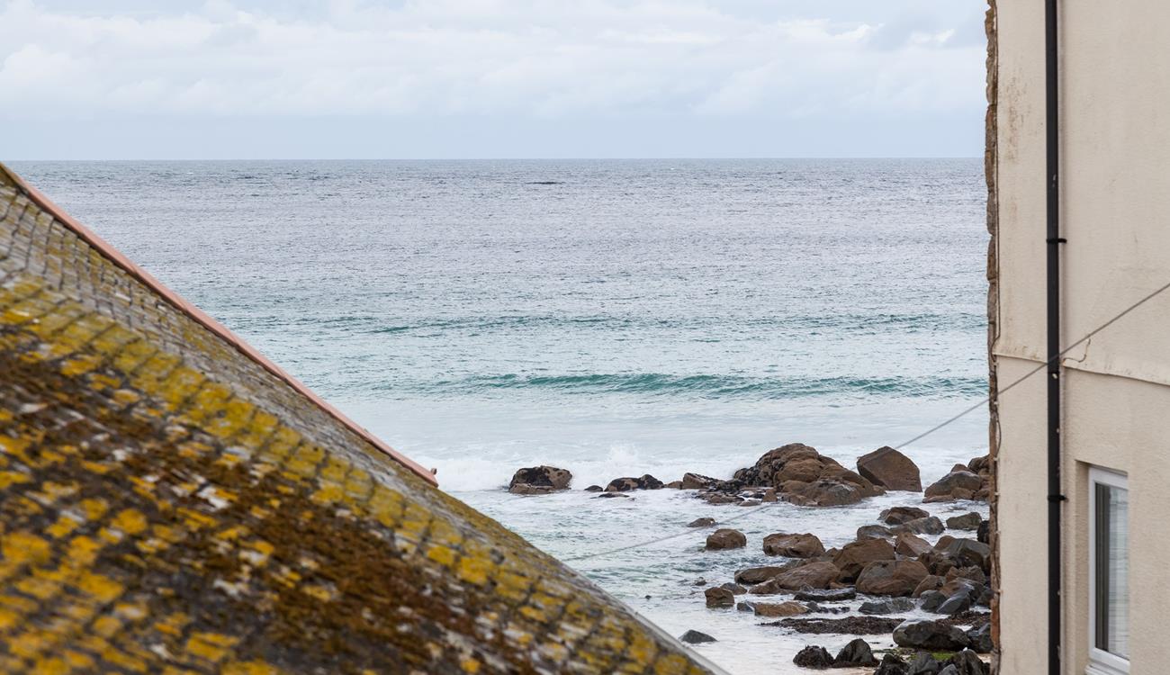 The sea view across the St Ives sea and the beach can be seen over the rooftops. 