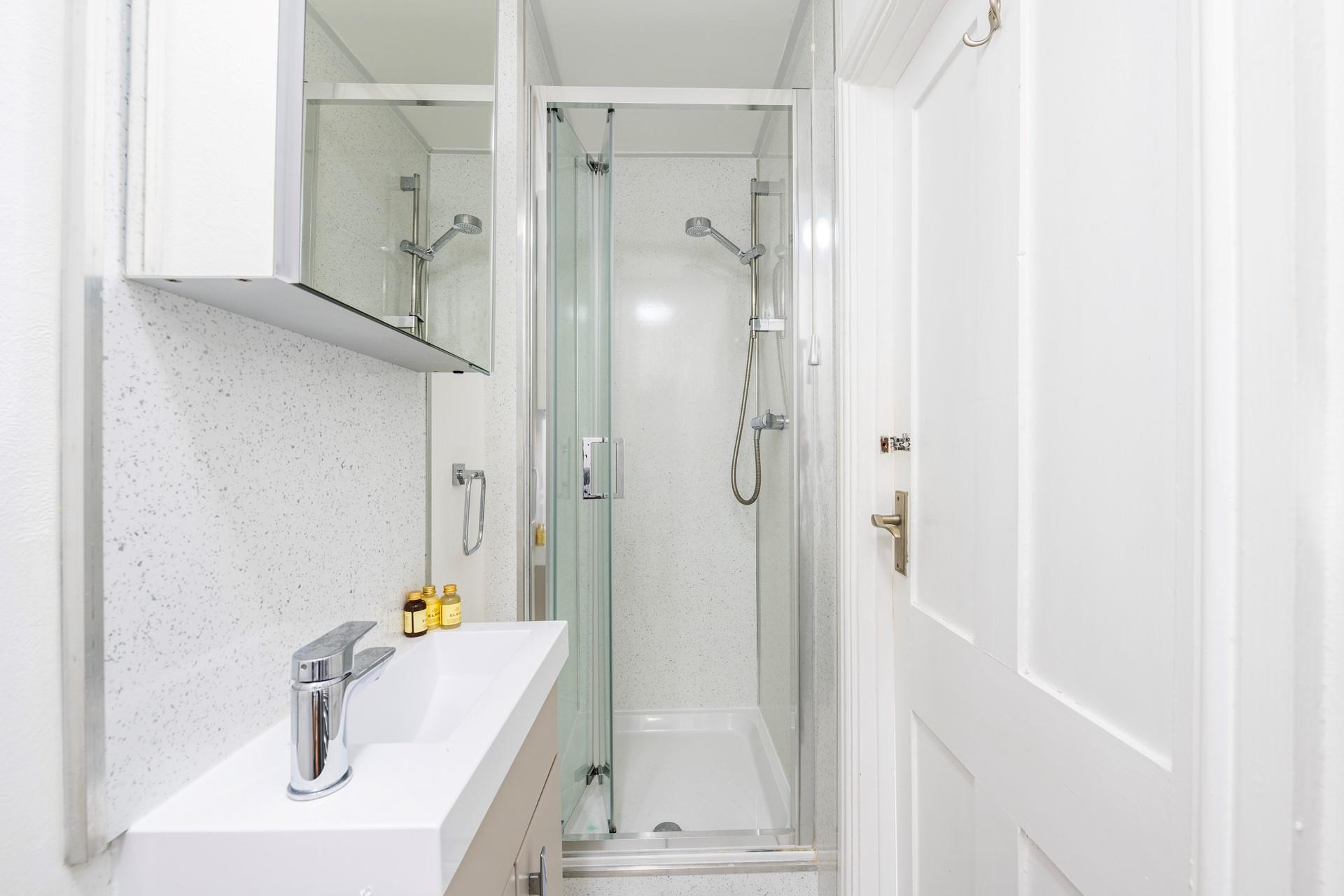 The en suite features an enclosed shower and benefits from a heated towel rail. 