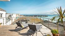 Relax on your rooftop sun lounger with a glass of something cold soaking up the sun in front of stunning views of St Ives.