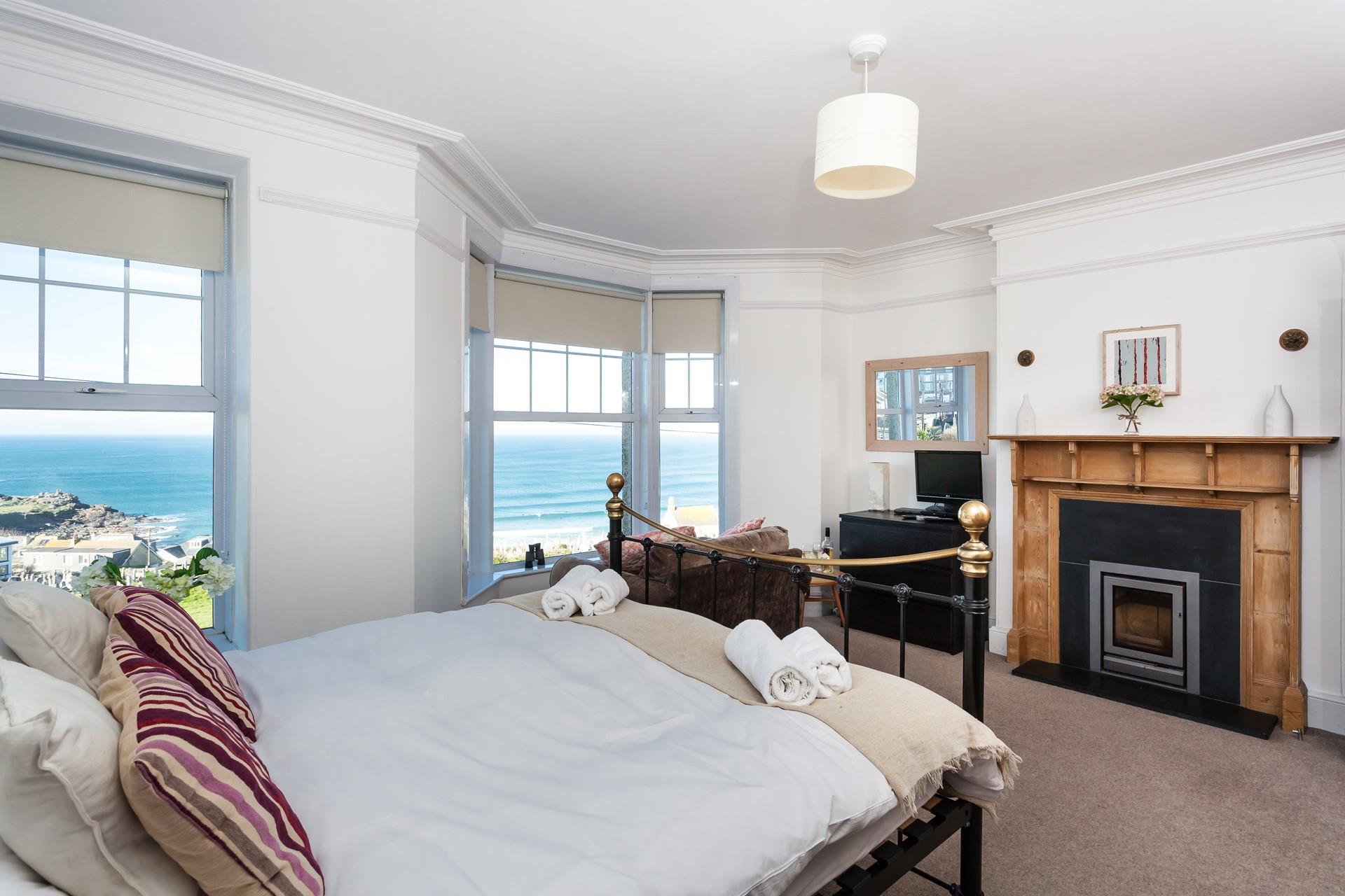 A beautiful bedroom with the original fireplace, bay windows, and high ceilings that make the most of the stunning view.