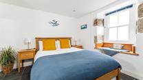 Exposed stone and classic wooden furniture give the bedroom a cute cottage feel, perfect for cosying up in.