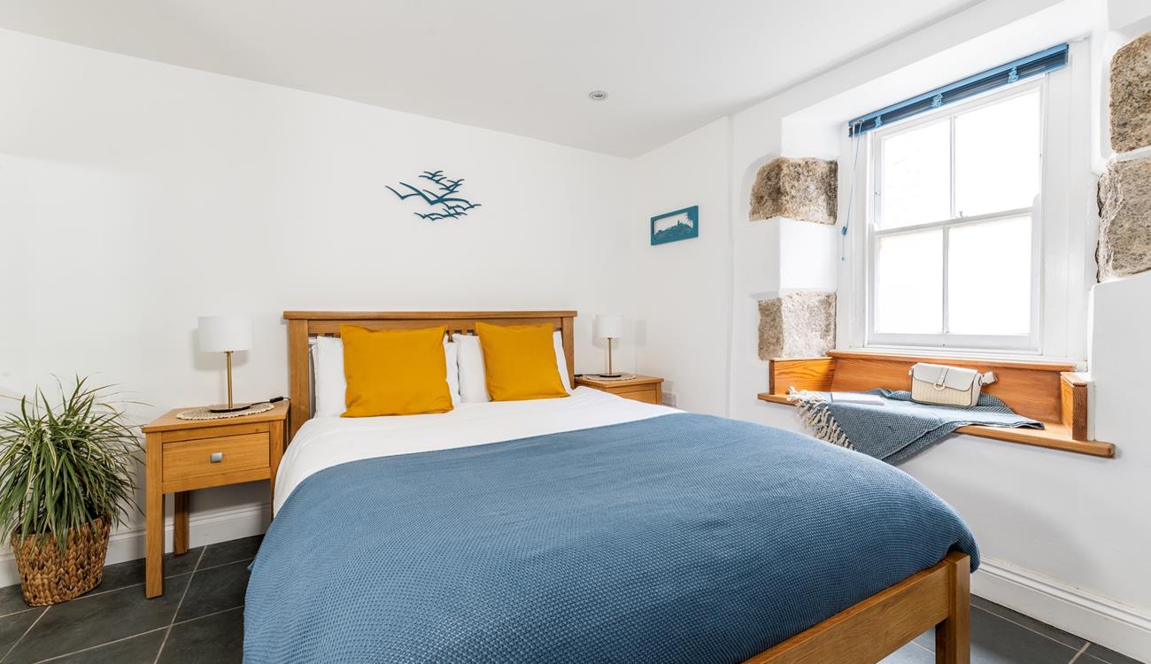 Exposed stone and classic wooden furniture give the bedroom a cute cottage feel, perfect for cosying up in.