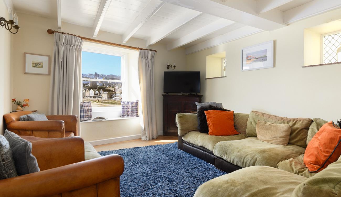 The cosy sitting room offers calming muted tones and ample seating, perfect for gathering together for a family games night.