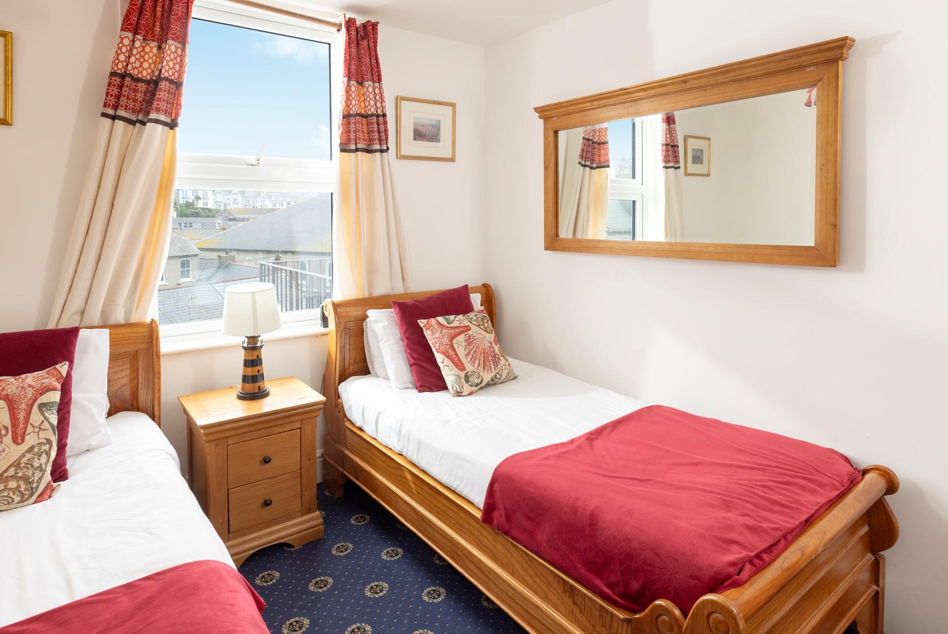 Comfortable twin bedroom with wooden furnishings and a red theme.