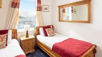 Comfortable twin bedroom with wooden furnishings and a red theme.