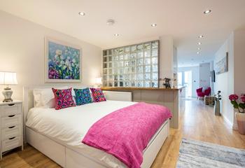 The bedroom is cleverly tucked away behind the frosted glass partition, offering privacy.