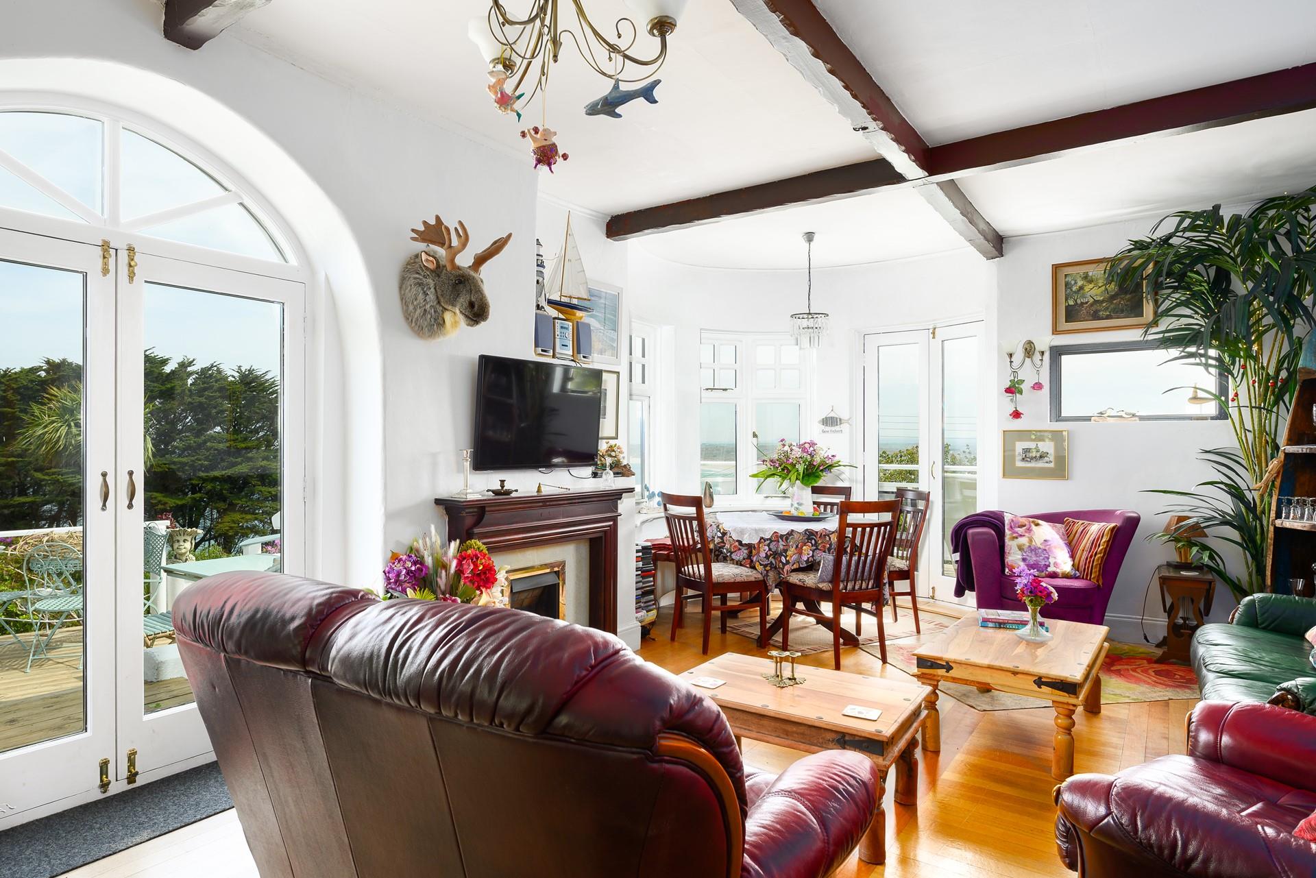 Large windows fill the sitting room with plenty of natural light, while the traditional wooden beams and fireplace add a cosy feel. 