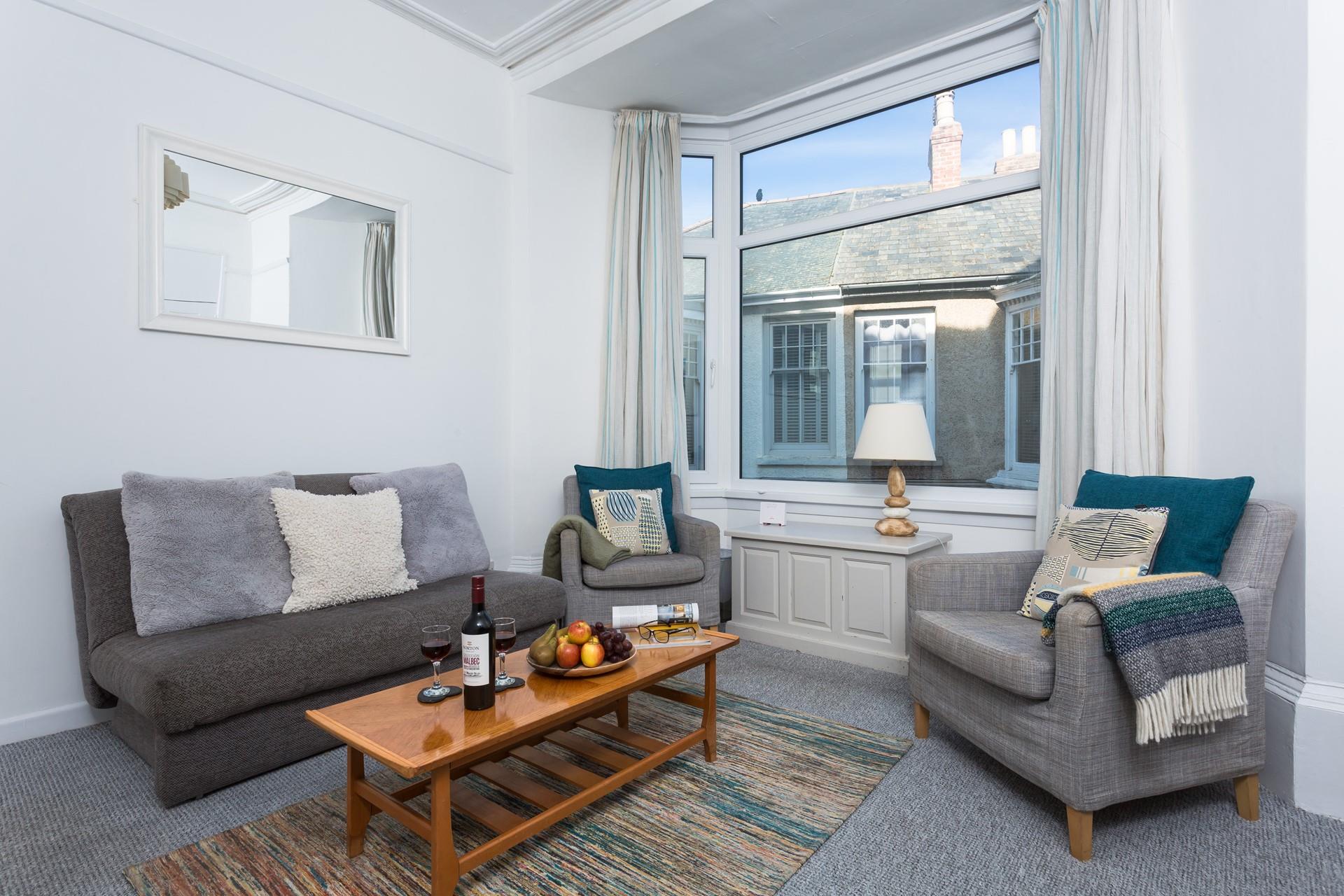 The large bay window brightens up the comfy sitting room and provides beautiful sea views.