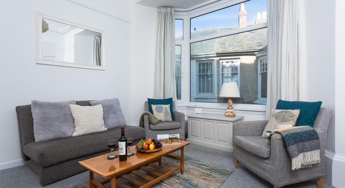 The large bay window brightens up the comfy sitting room and provides beautiful sea views.