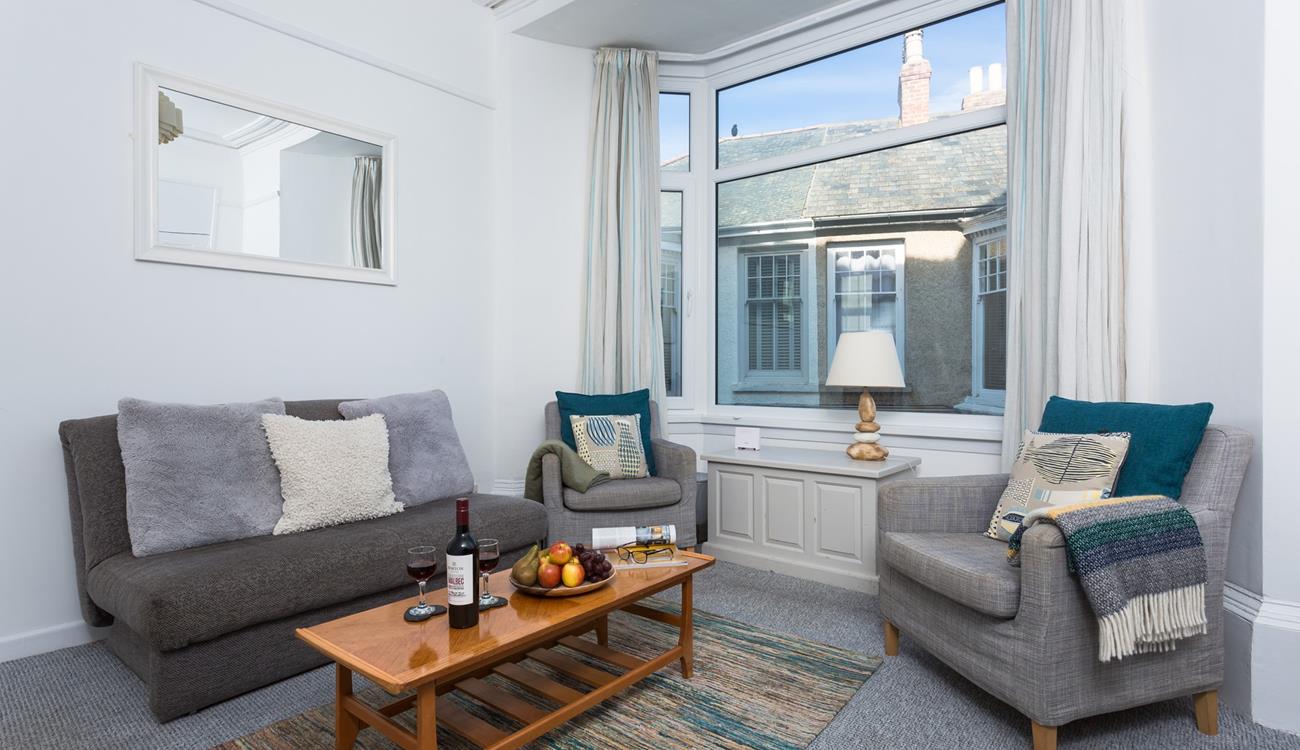 The large bay window brightens up the comfy sitting room and provides beautiful sea views.