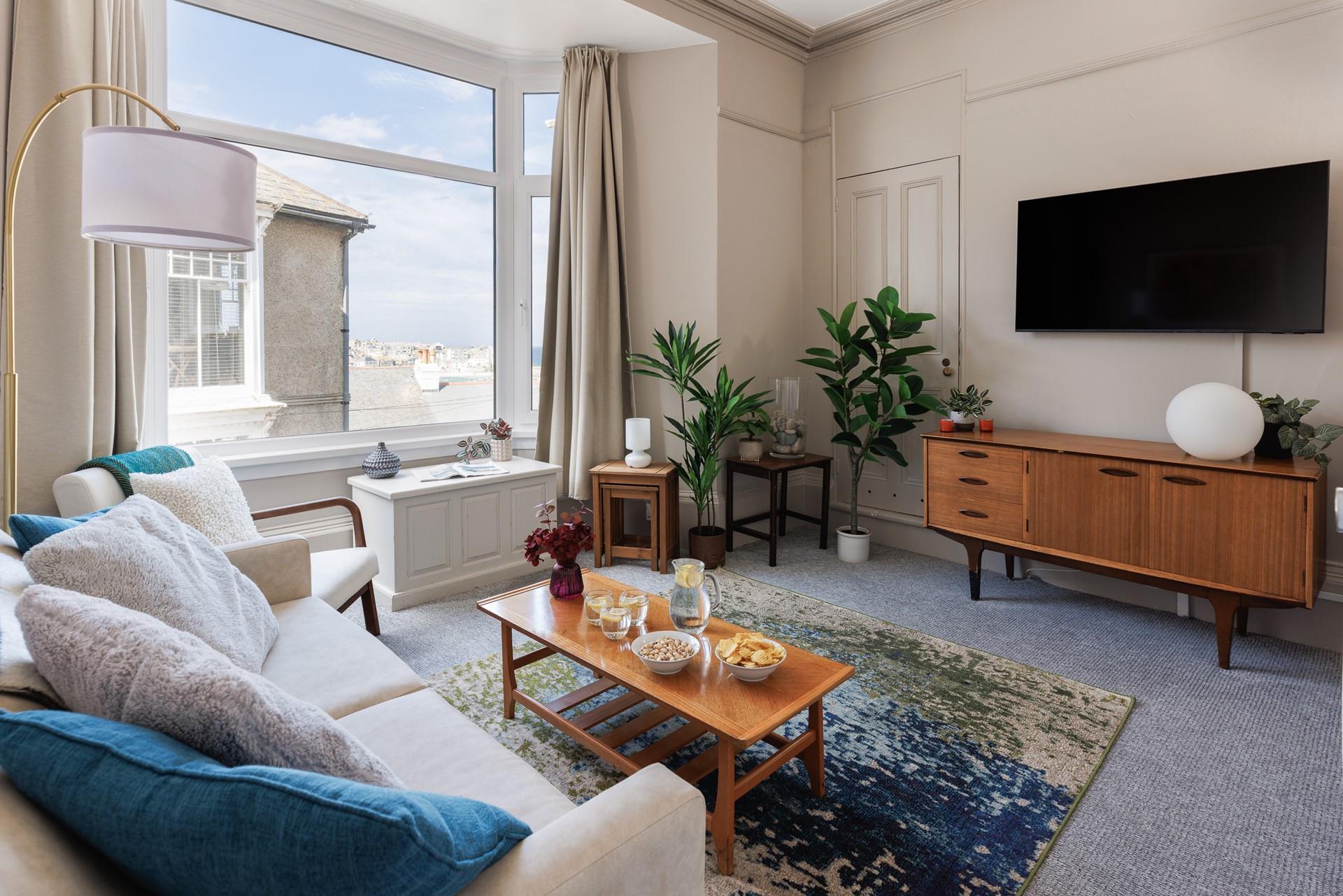 The large bay window brightens up the comfy sitting room and provides beautiful sea views.