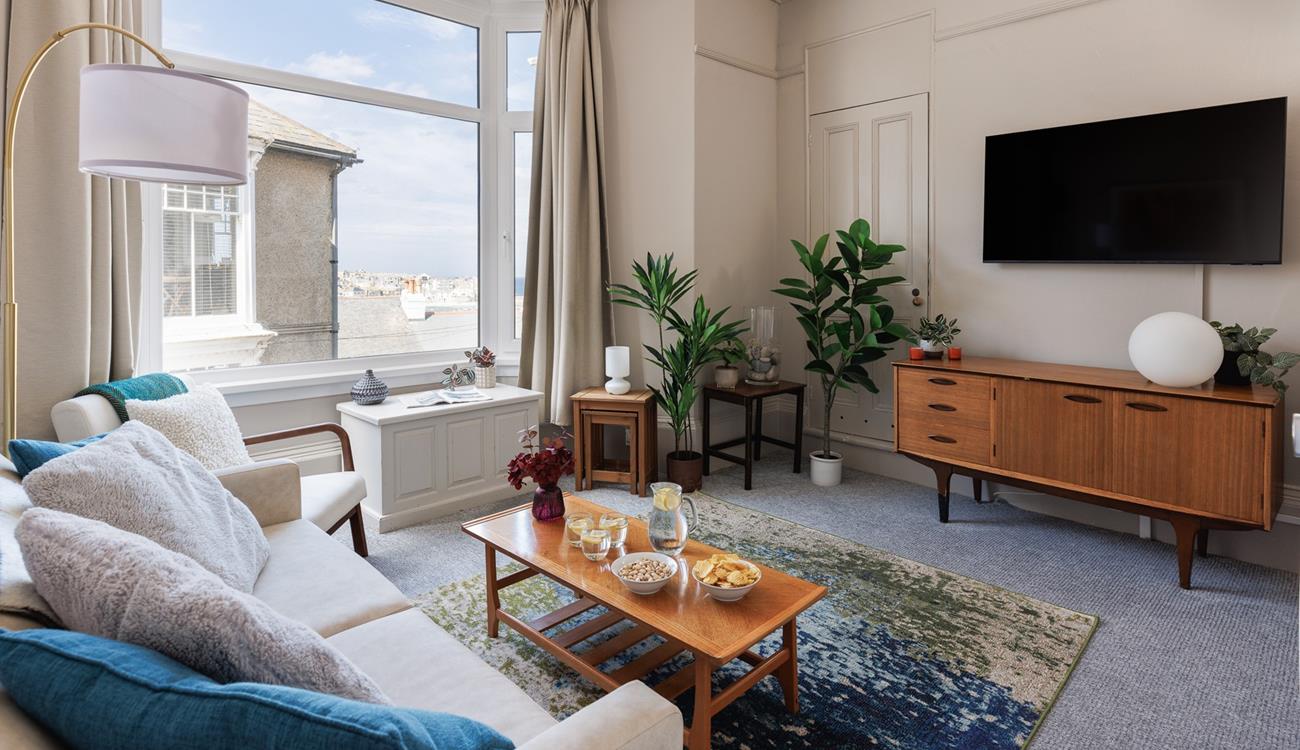 The large bay window brightens up the comfy sitting room and provides beautiful sea views.