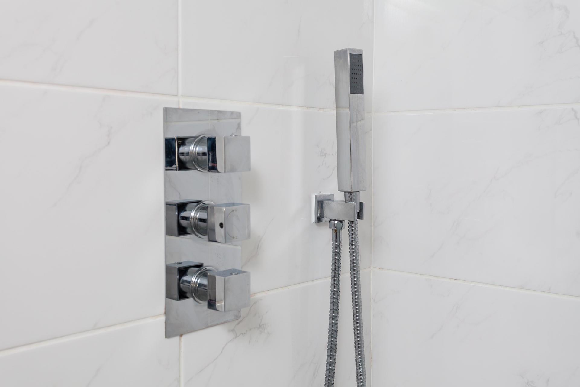 The shower attachment and temperature controls in the shower room.