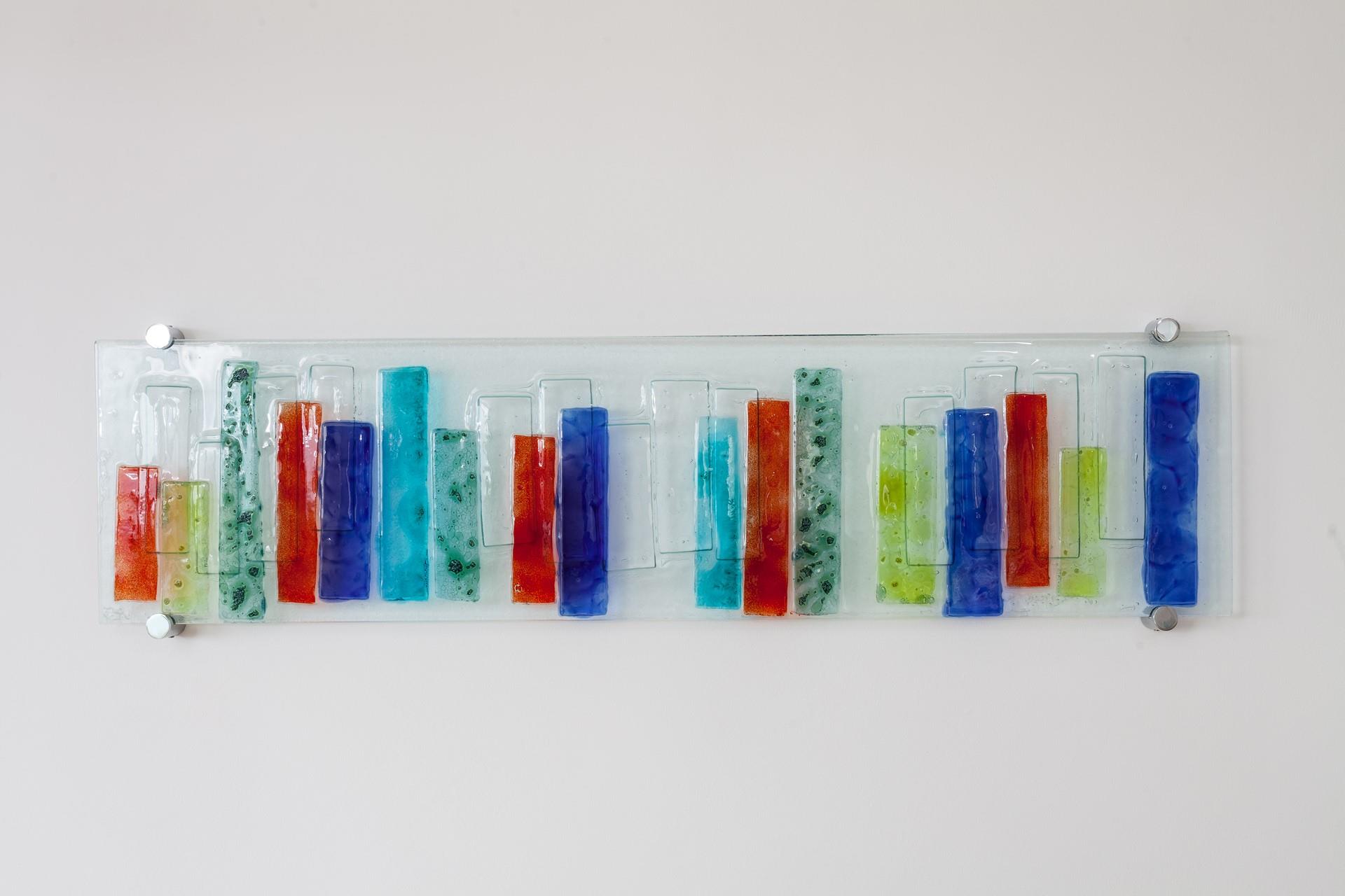 Contemporary y and colourful fused glass wall art can be found around the apartment.