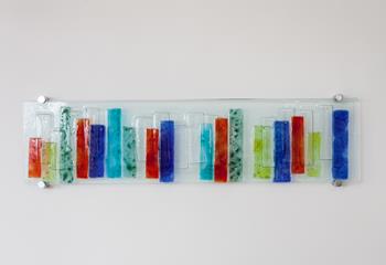 Contemporary y and colourful fused glass wall art can be found around the apartment.