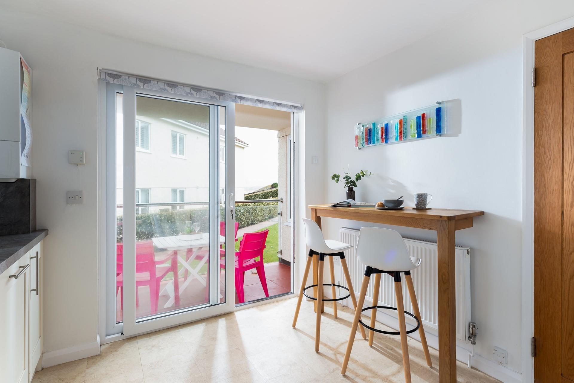 Open the patio doors and enjoy breakfast at the convenient breakfast bar or outside on the bright pink chairs.