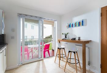 Open the patio doors and enjoy breakfast at the convenient breakfast bar or outside on the bright pink chairs.