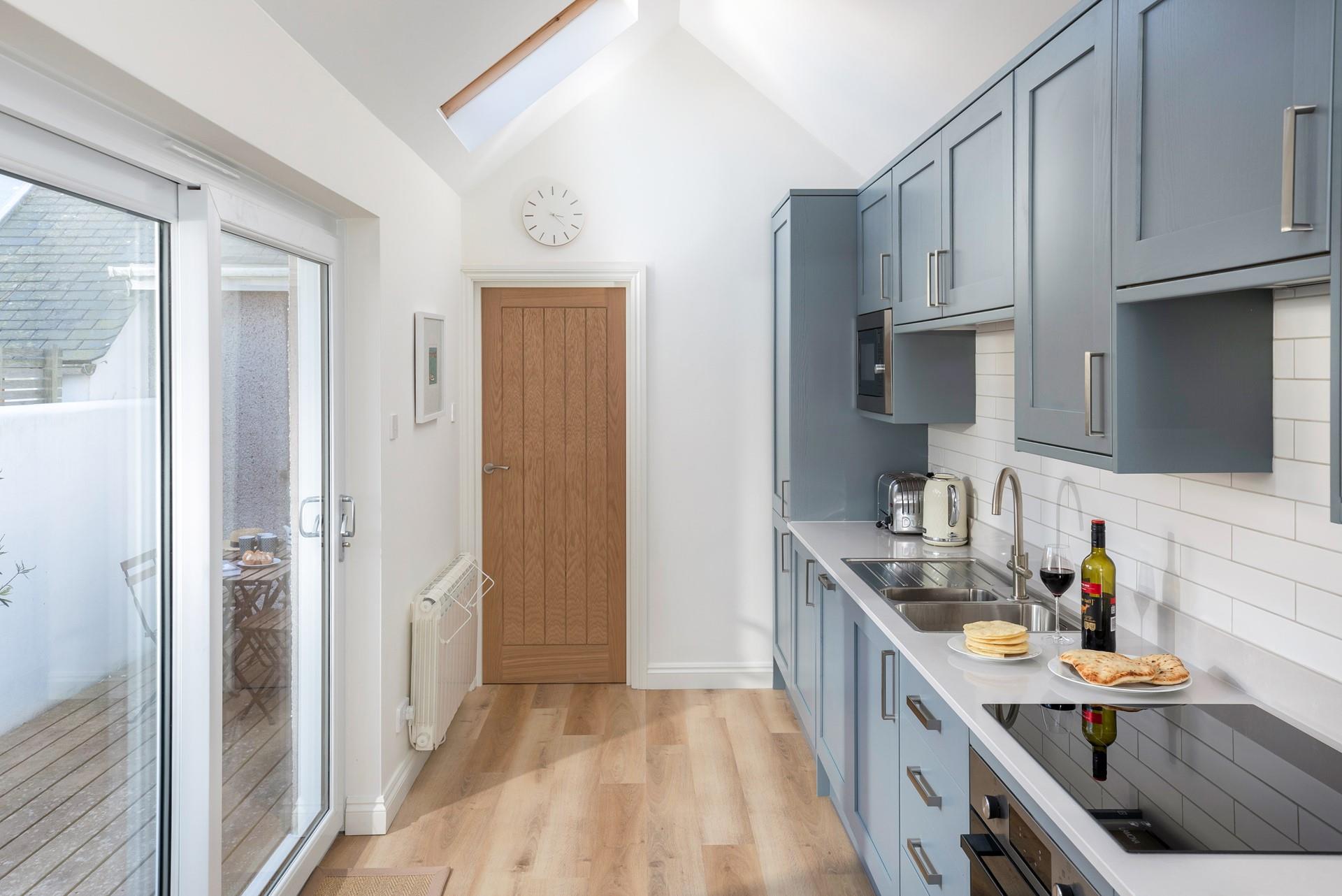 The stylish kitchen has patio doors onto an enclosed decked area.