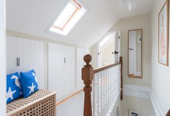 The landing is spacious and light with white painted stairway spindles and natural wood banister and newels.