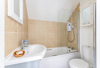 The warm-toned bathroom with bath and shower over is ideal for pampering yourself.