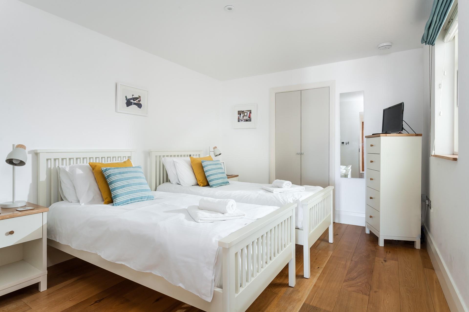 Bedroom 2 is decorated with a pop of colour with cosy cushions.