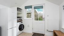 The utility has a washing machine and fridge.