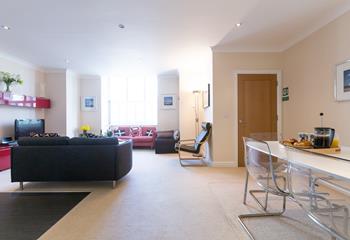 The open plan sitting/dining/kitchen area is light and spacious. The door shown is the front door. 