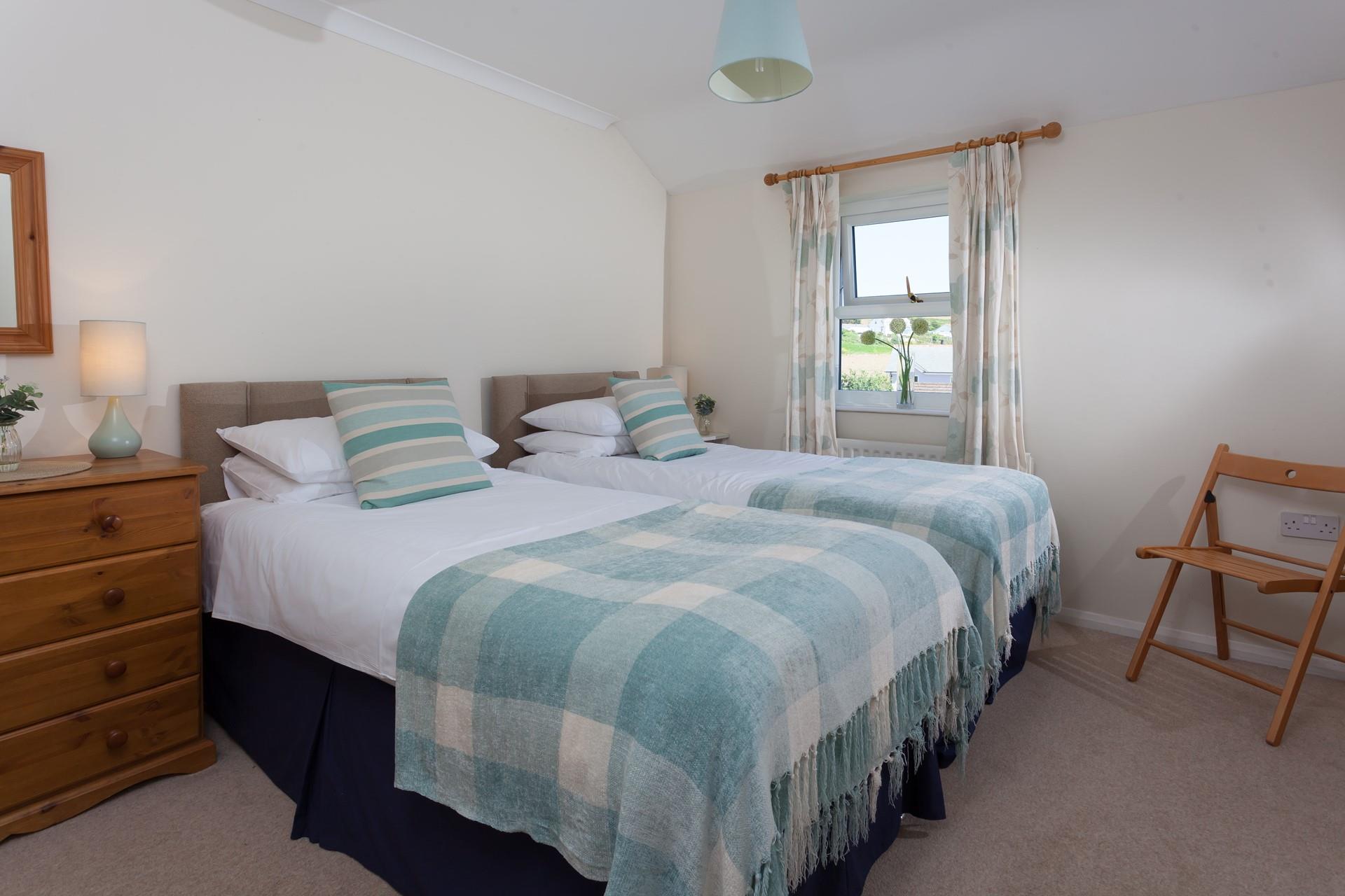 The second bedroom features twin beds, with sea views from the window. 