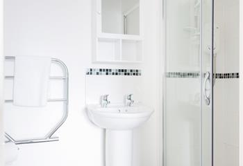 The bright white bathroom with monochromatic tiles is the perfect space to freshen up for the day ahead.