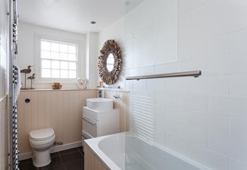 The stylish bathroom benefits from a bath with a shower.