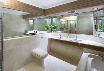 Sleek and spacious, the family bathroom features a bath, a separate enclosed shower, double washbasins, a WC and large mirrors. 