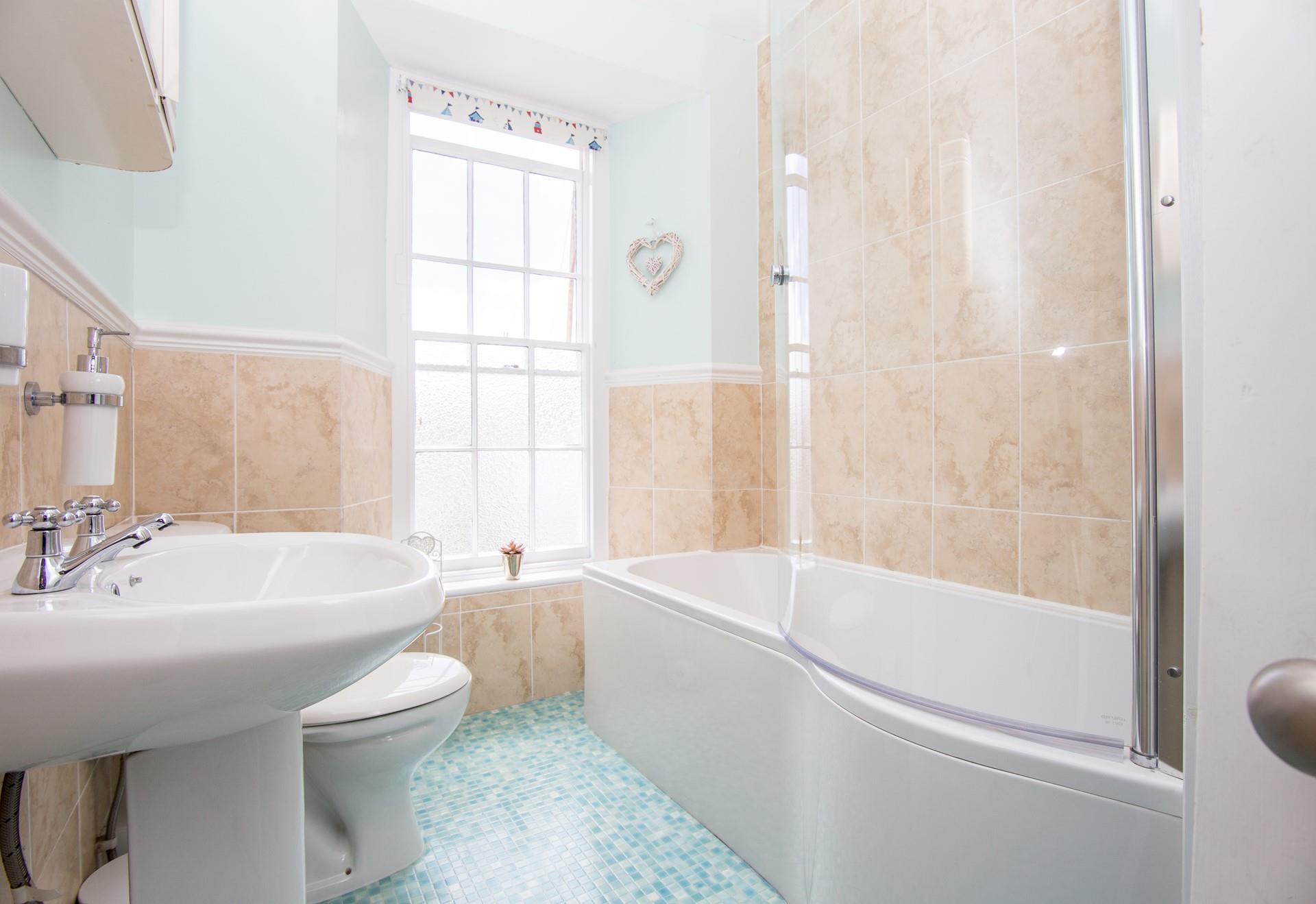 Treat yourself to a relaxing bubble bath in the spacious coastal-themed bathroom. 