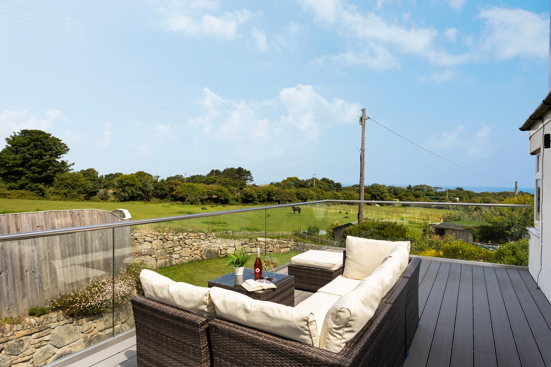 Relax on the large balcony, glass of wine in hand, overlooking the meadows and distant sea views. 