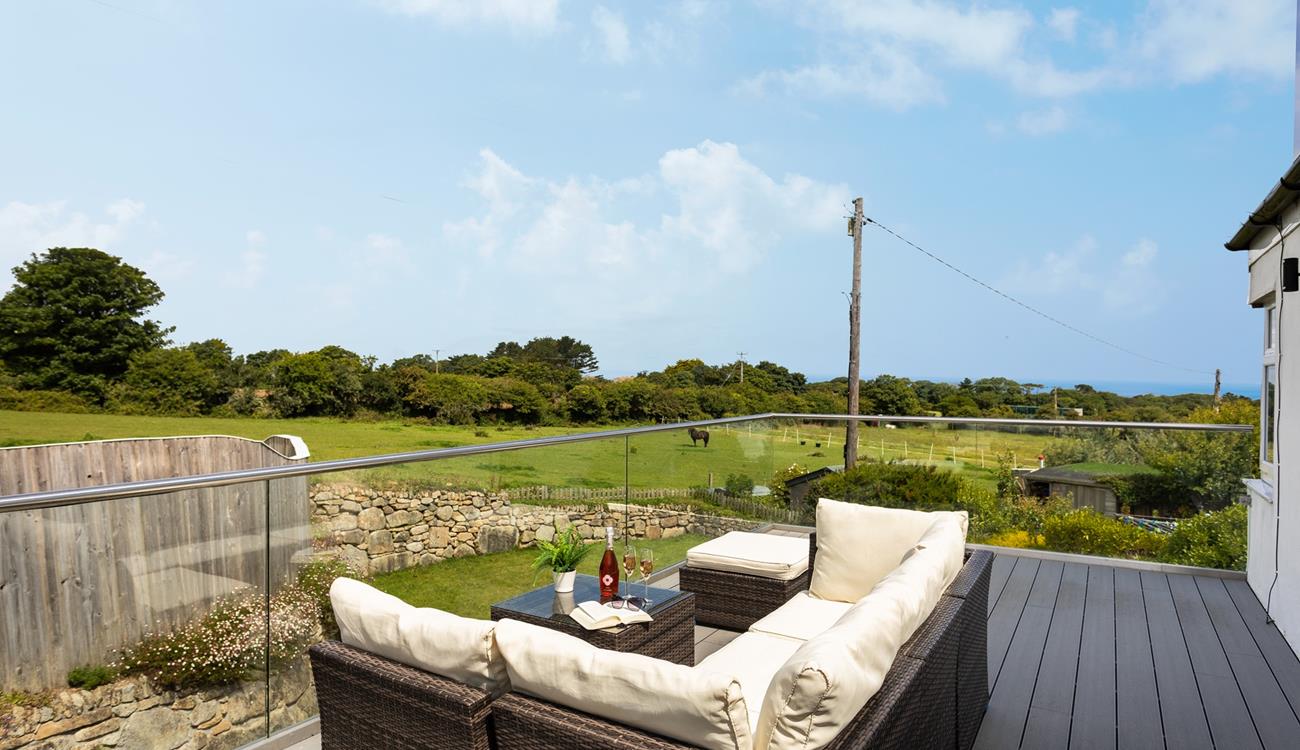 Relax on the large balcony, glass of wine in hand, overlooking the meadows and distant sea views. 