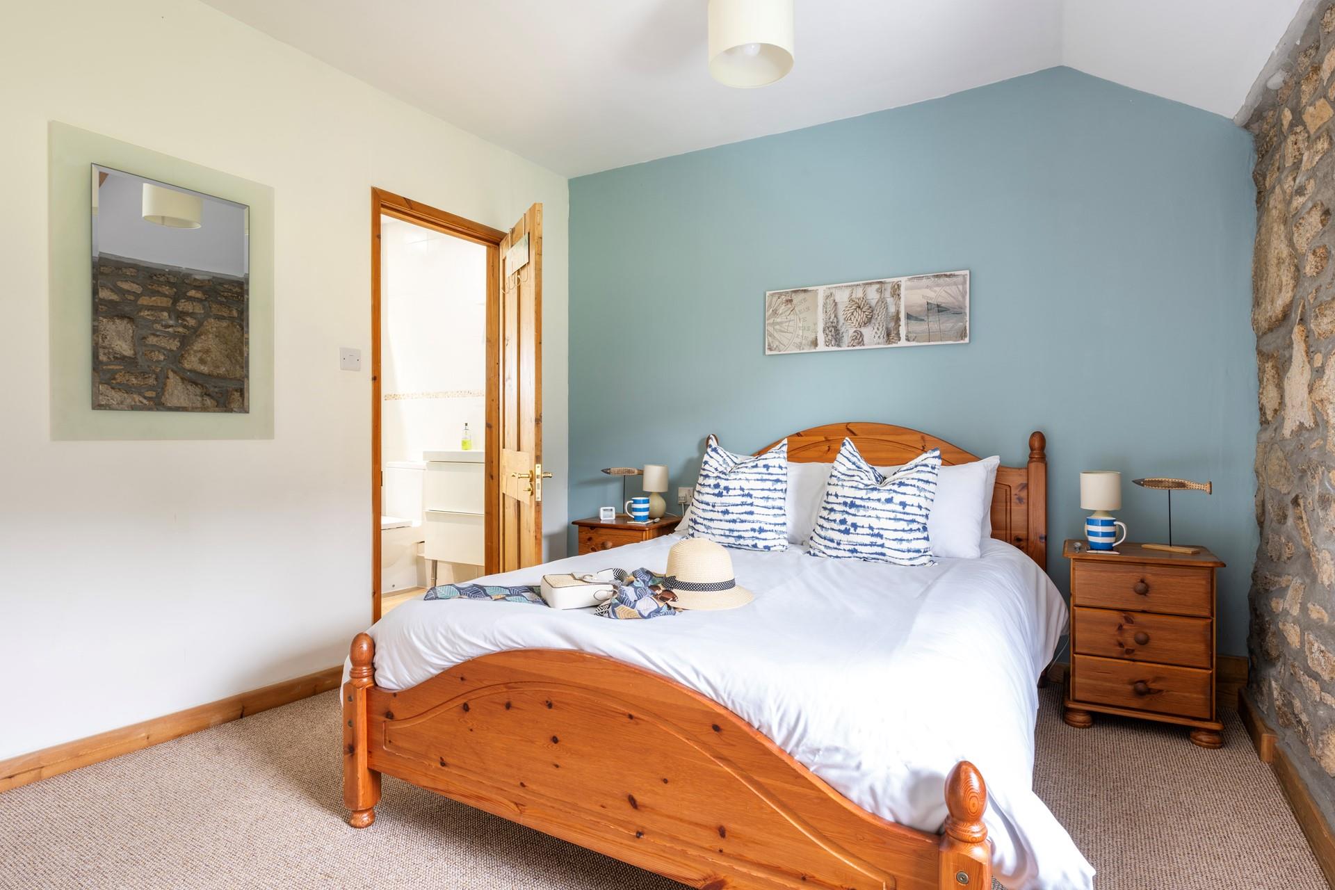 The stunning double bedroom has exposed wooden beams and a stone wall. 