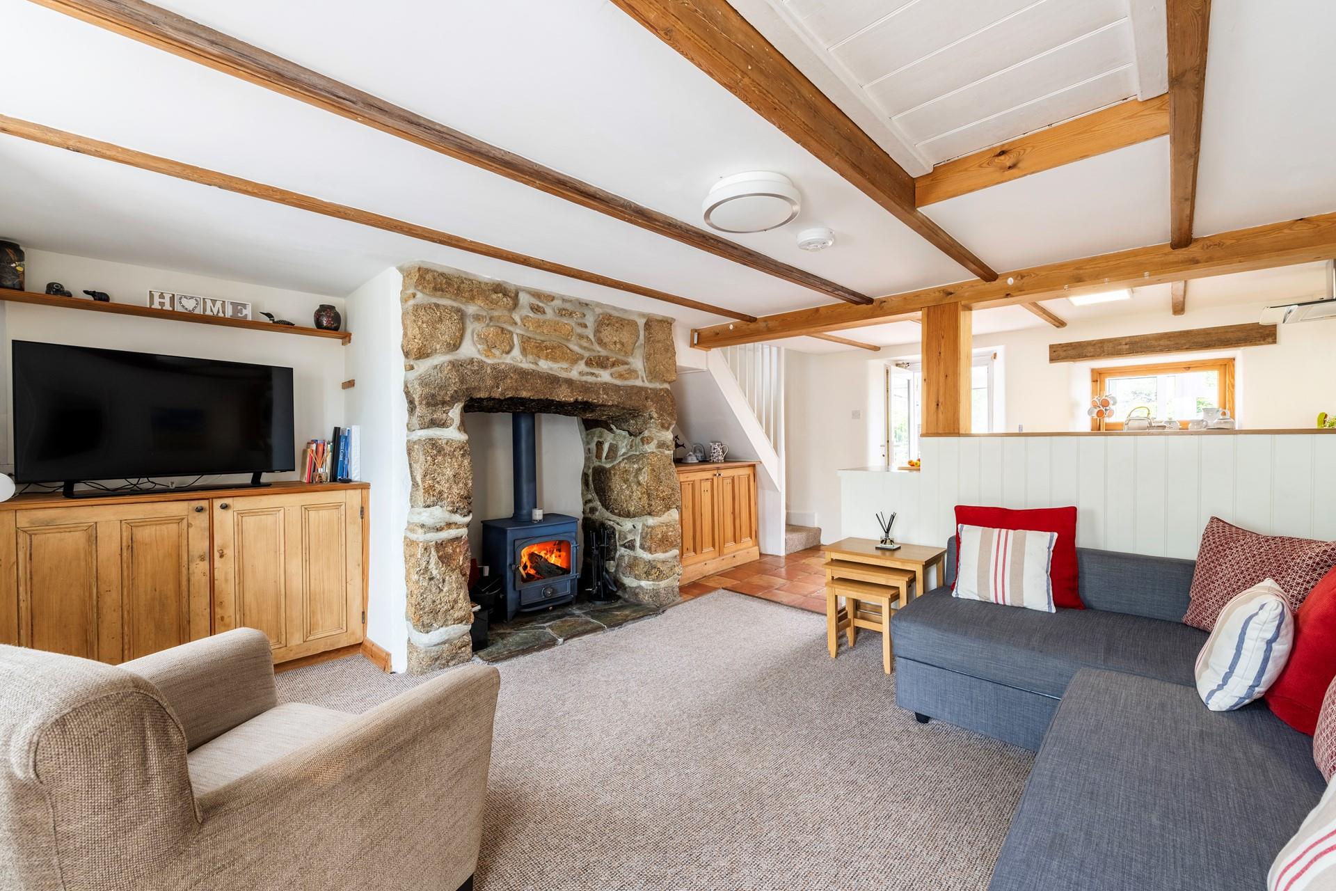 An exposed stone inglenook fireplace with woodburner creates a very cosy atmosphere for this sitting room. 