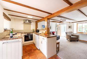 A homely open plan sitting and kitchen area with exposed wooden beams provide a space to cook up delicious meals. 