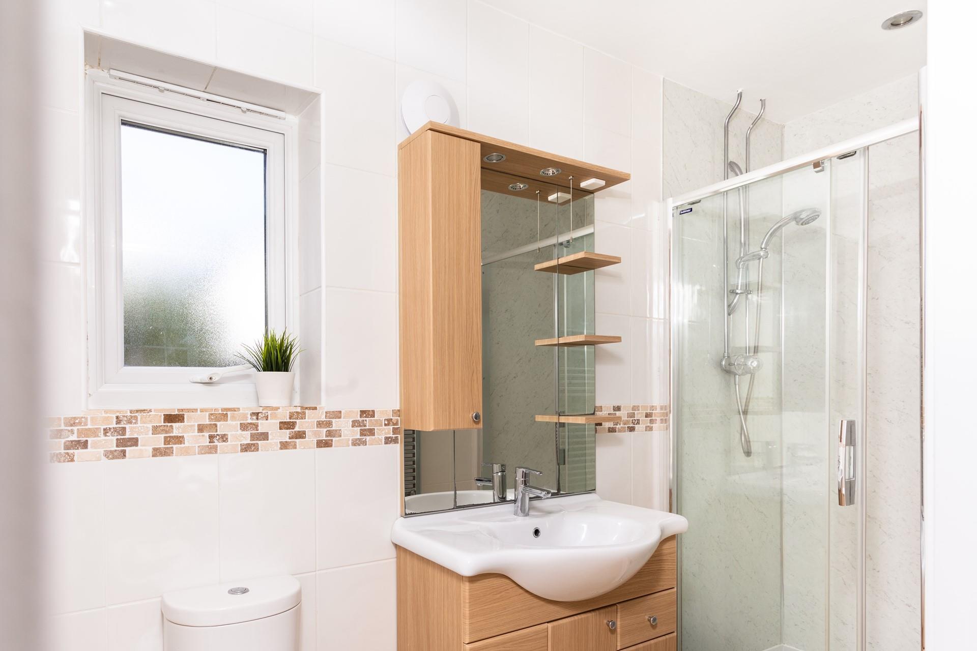 The ensuite shower room has an enclosed mains shower and a washbasin with fully-fitted cupboards below and above.