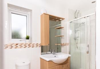 The ensuite shower room has an enclosed mains shower and a washbasin with fully-fitted cupboards below and above.