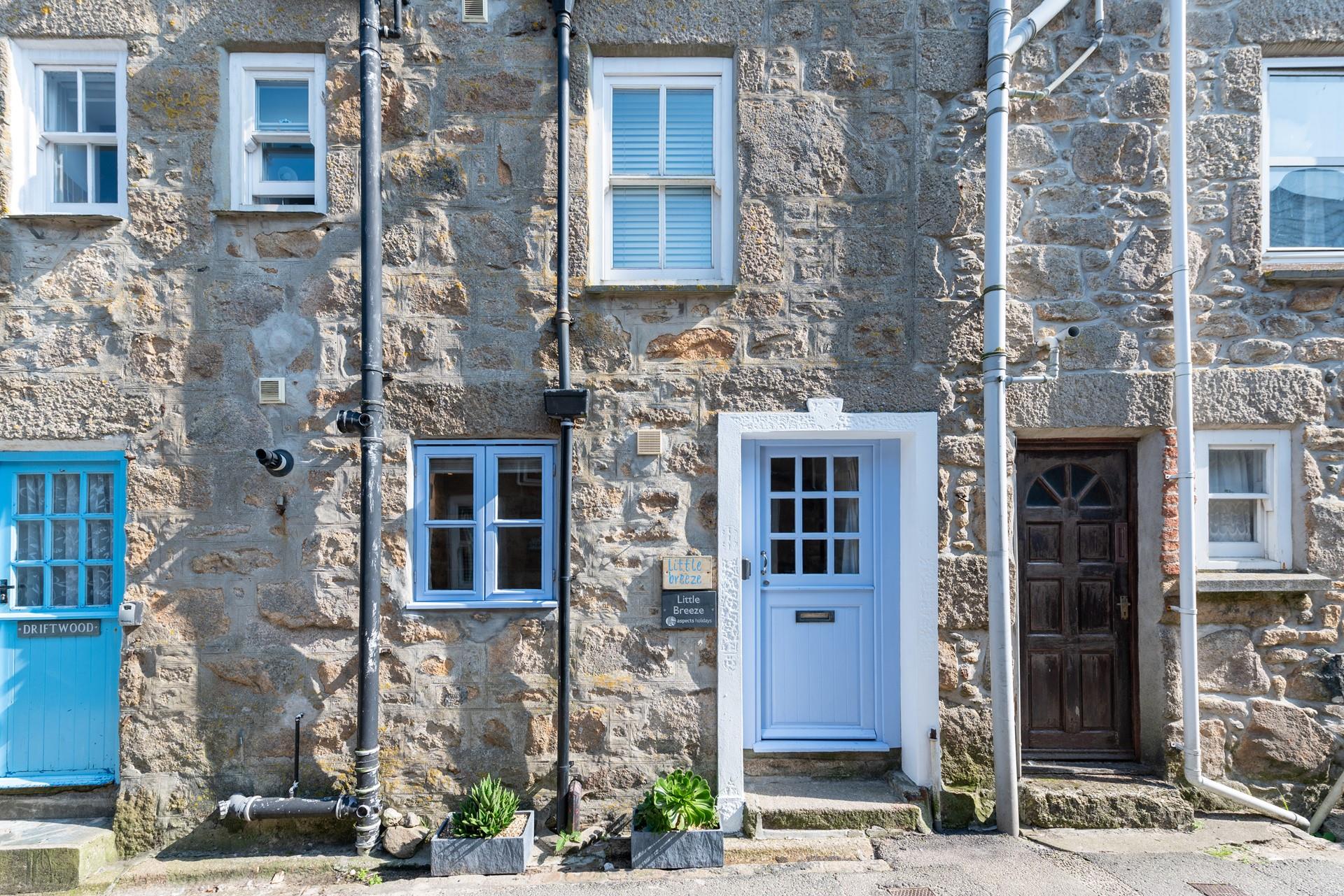 Little Breeze has a stone-faced facade with a Cornish blue stable entrance door.