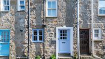 Little Breeze has a stone-faced facade with a Cornish blue stable entrance door.