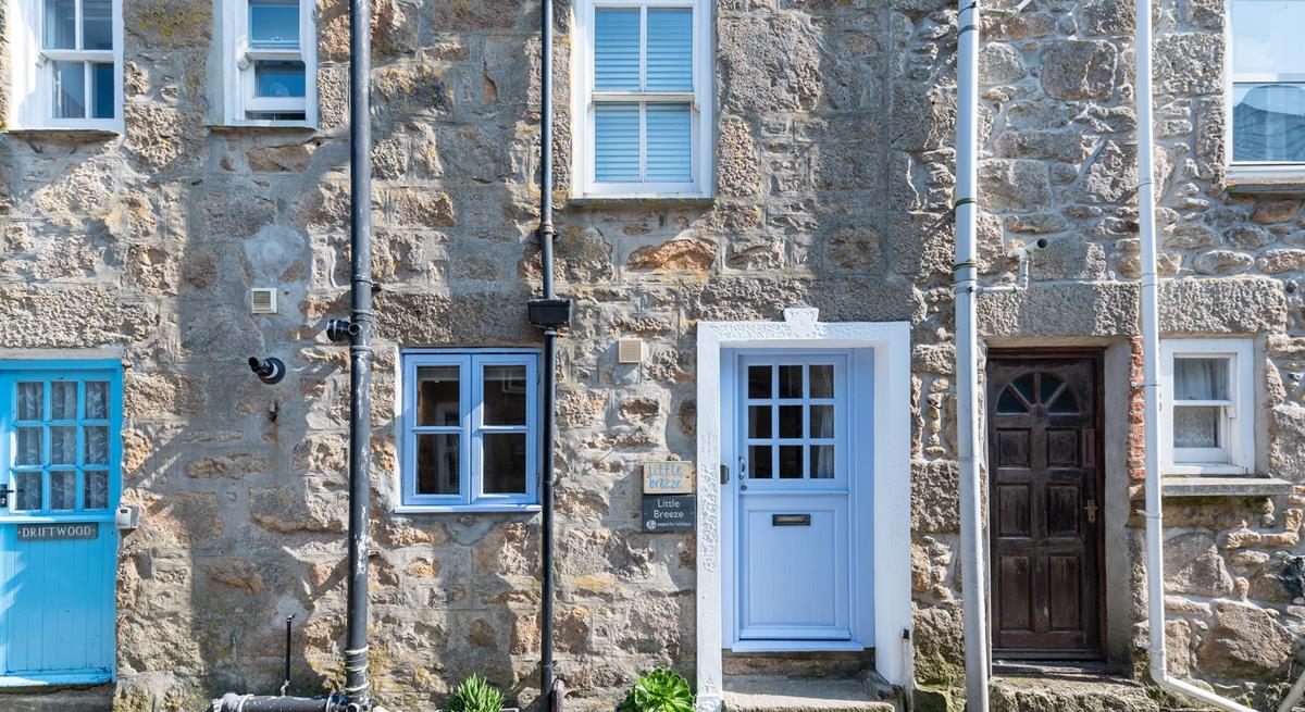 Little Breeze has a stone-faced facade with a Cornish blue stable entrance door.