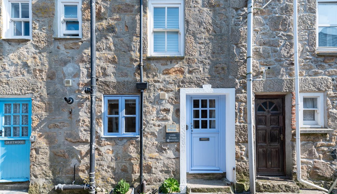 Little Breeze has a stone-faced facade with a Cornish blue stable entrance door.