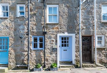 Little Breeze has a stone-faced facade with a Cornish blue stable entrance door.