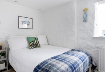 The painted stone walls give the bedroom a quaint, cottage-like feel.