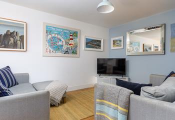 The living area is a relaxing space with bursts of colour from coastal artwork.
