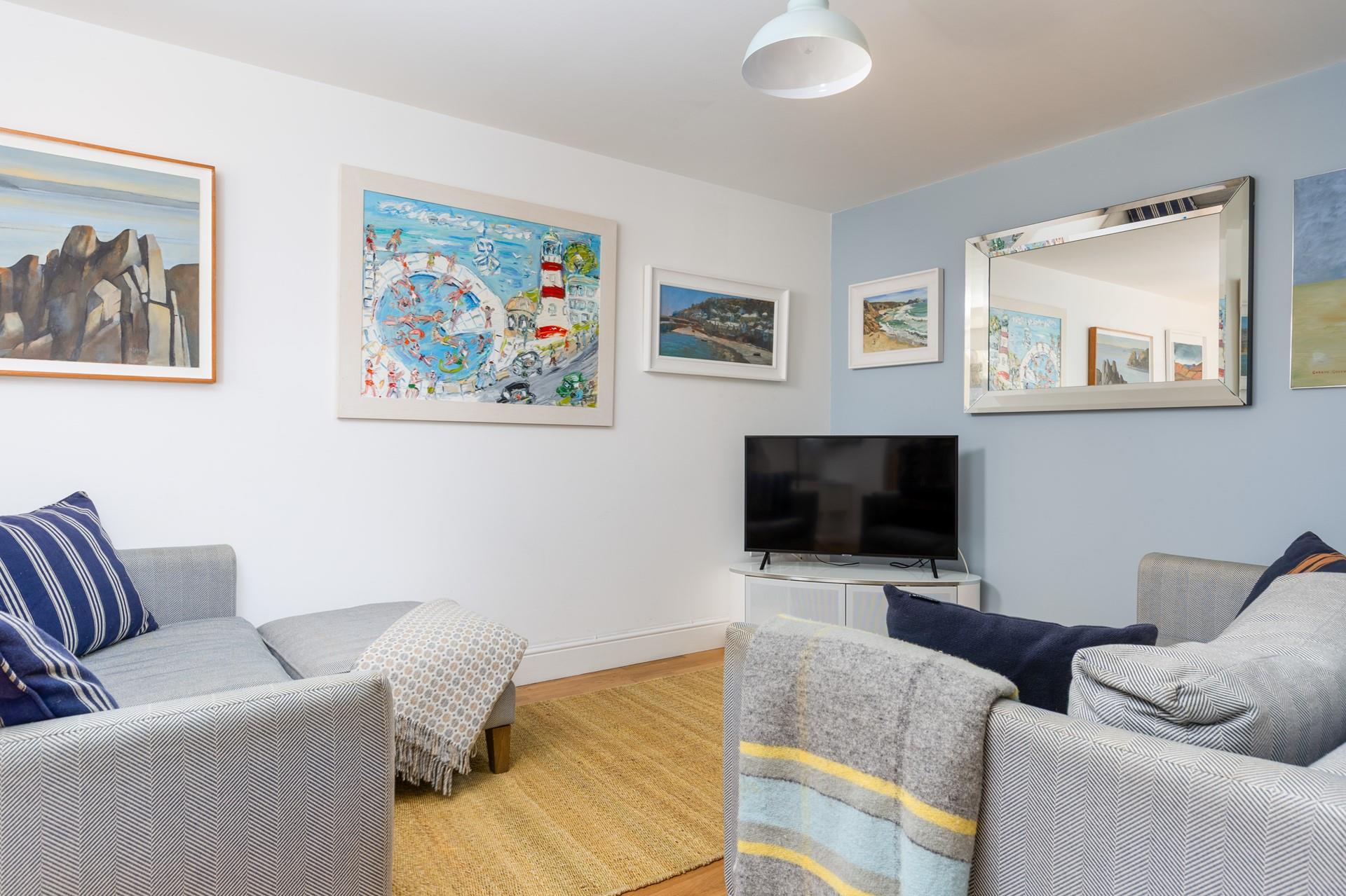 The living area is a relaxing space with bursts of colour from coastal artwork.