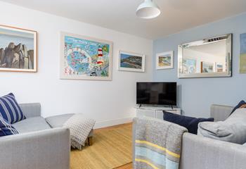 The living area is a relaxing space with bursts of colour from coastal artwork.